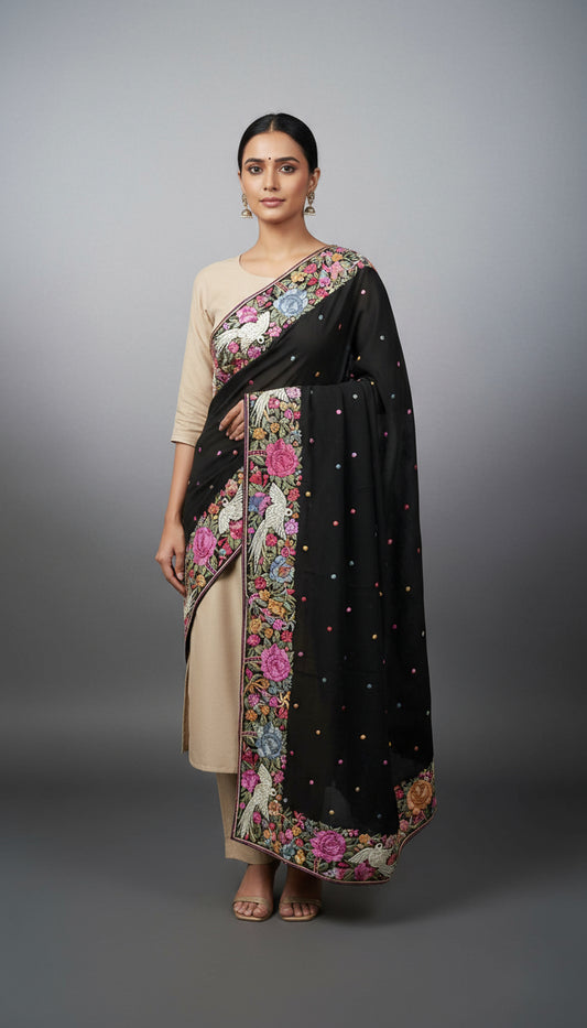 Woman wearing a black saree with floral patterns on a gray background