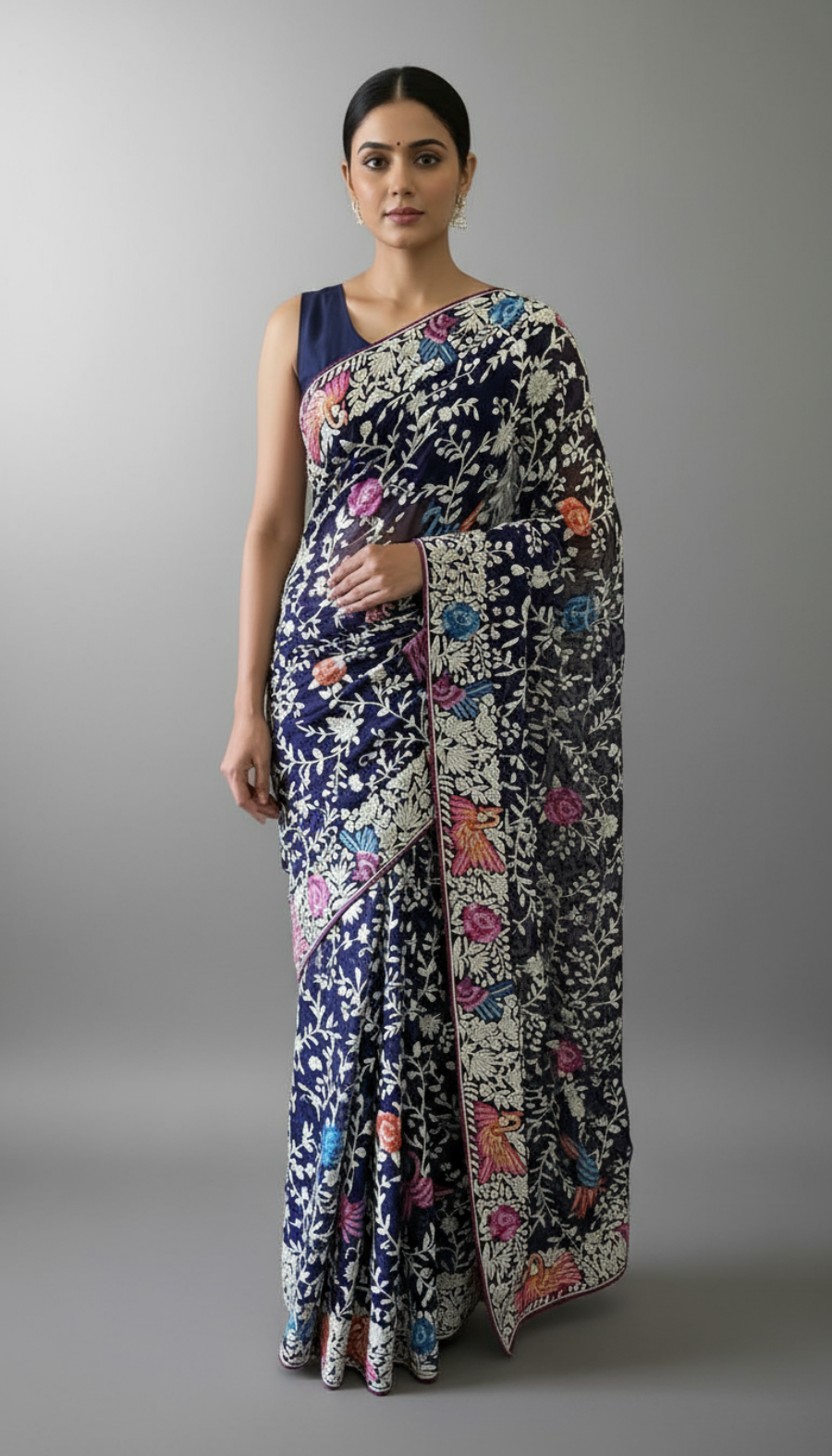 Woman wearing a floral  parsi gara saree with a gray background