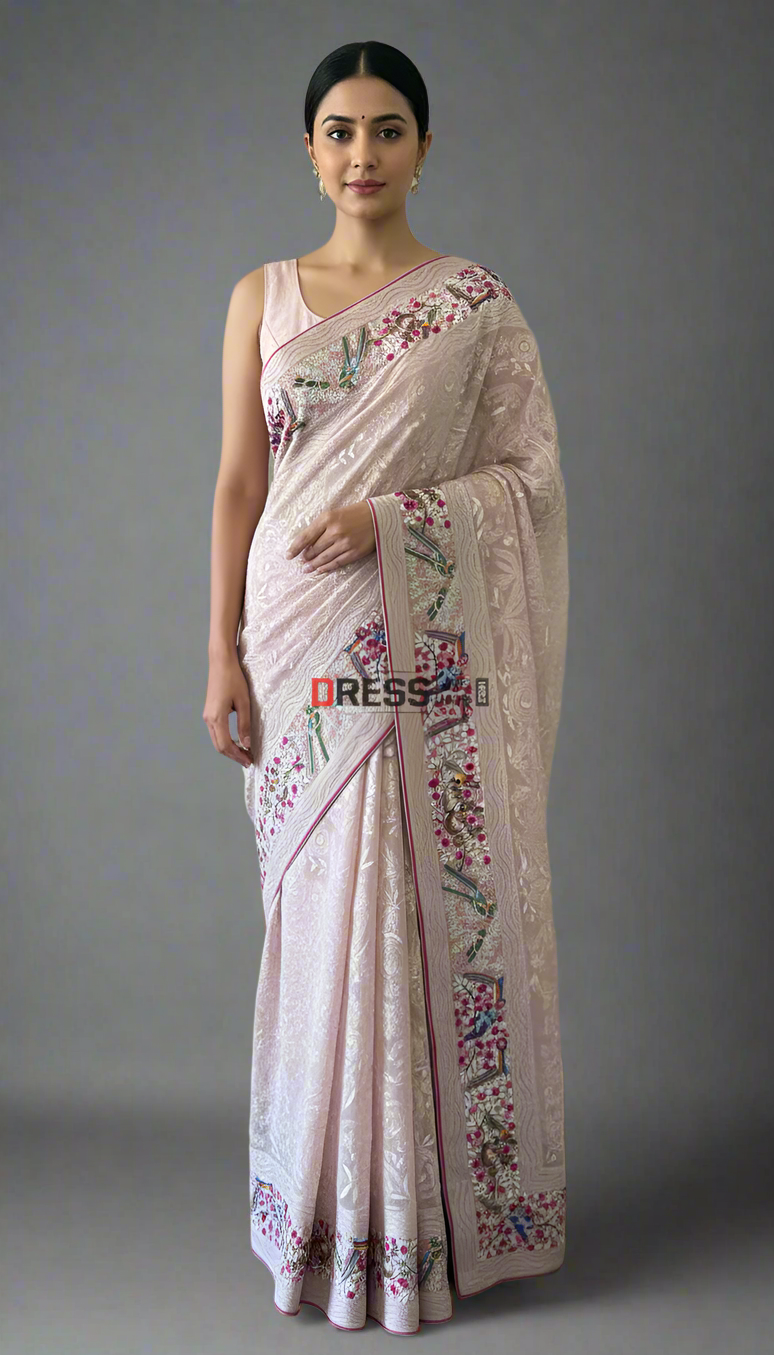 Woman wearing a light pink saree with floral embroidery against a neutral background