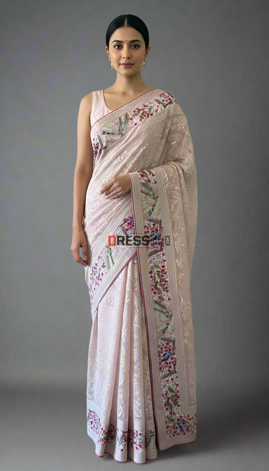 Woman wearing a light pink saree with floral embroidery against a neutral background