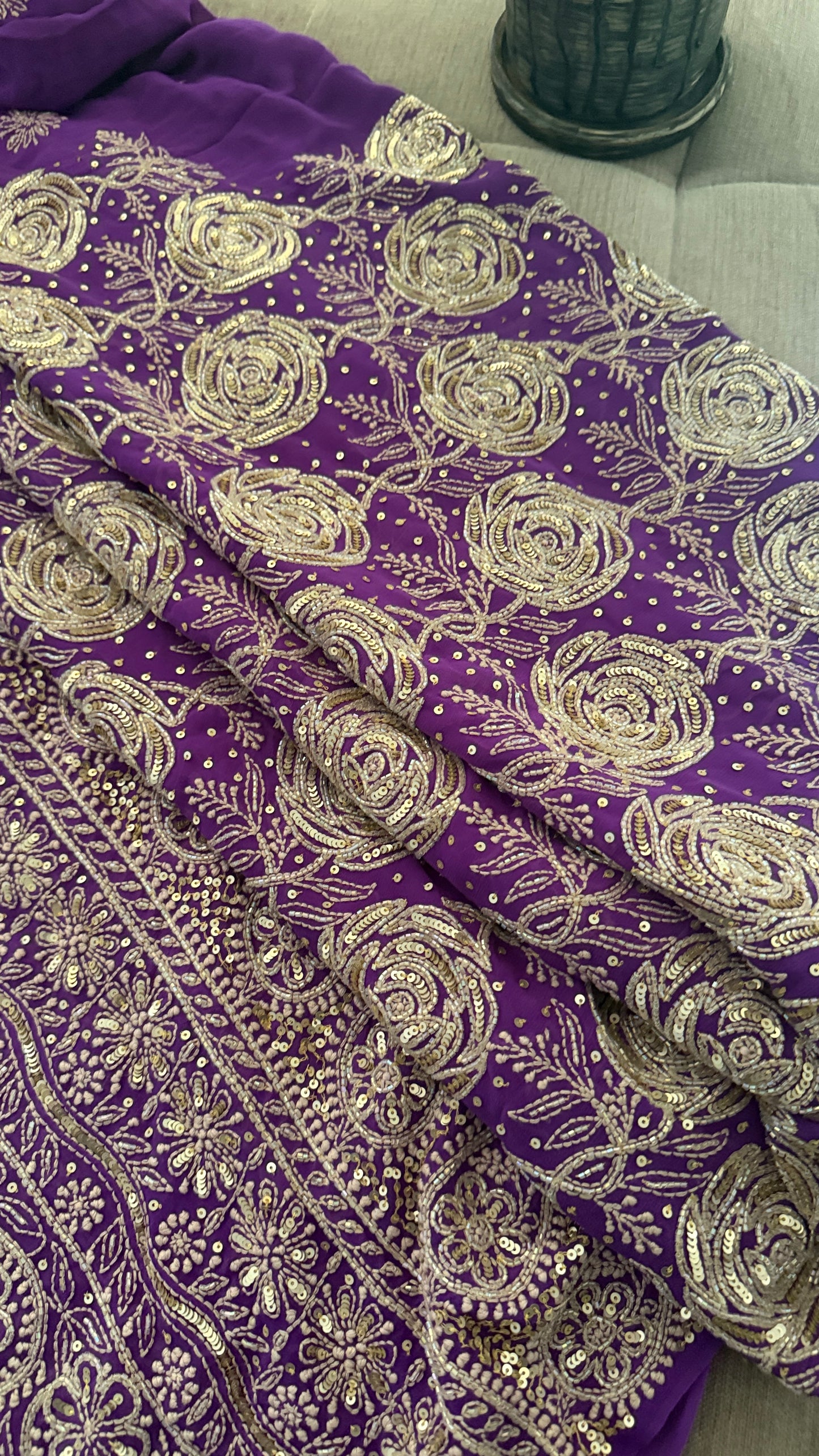 Purple fabric with intricate silver floral embroidery and sequin detailing, draped to show the texture and pattern.